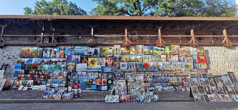 Many colorful paintings hang for sale on a wall, Krakow, Poland