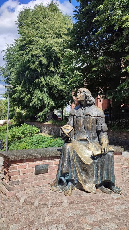Bronze statue of Nicolaus Copernicus on a stone bench in Olsztyn, Masuria, Poland