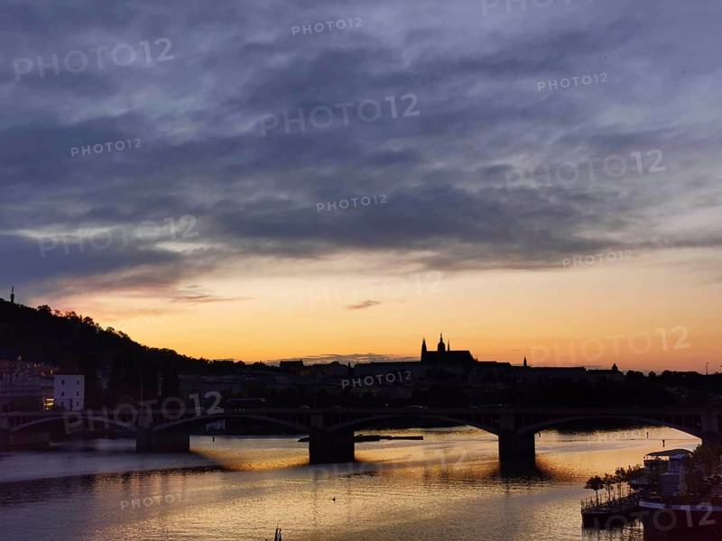 Dramatic orange sunset over the Vltava with silhouettes of Charles Bridge and Hradcany, Prague, Czech Republic