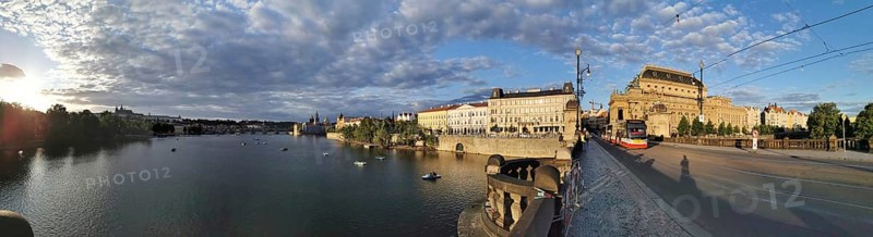 Extensive city panorama of Prague with the Vltava River, a bridge with tram and historic buildings under a cloudy sky, Prague, Czech Republic