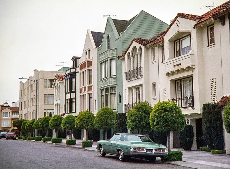 Mediterranean and Spanish Colonial Revival-style row houses stands in the Marina District of San Francisco, captured in 1976. A dark green 1972 Chevrolet Impala