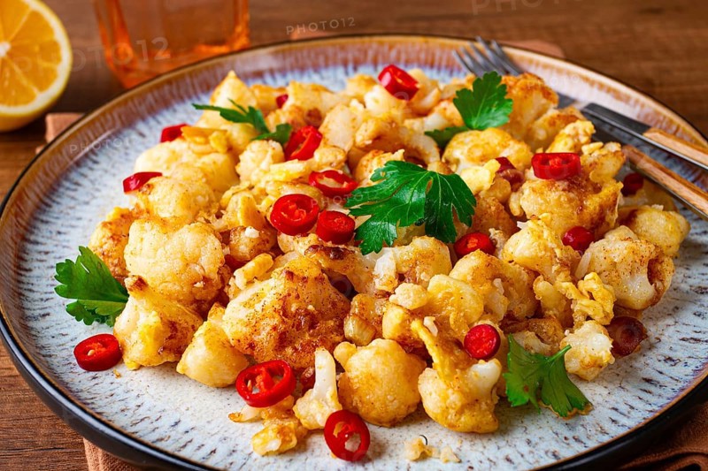Spicy fried cauliflower served on a wooden countertop