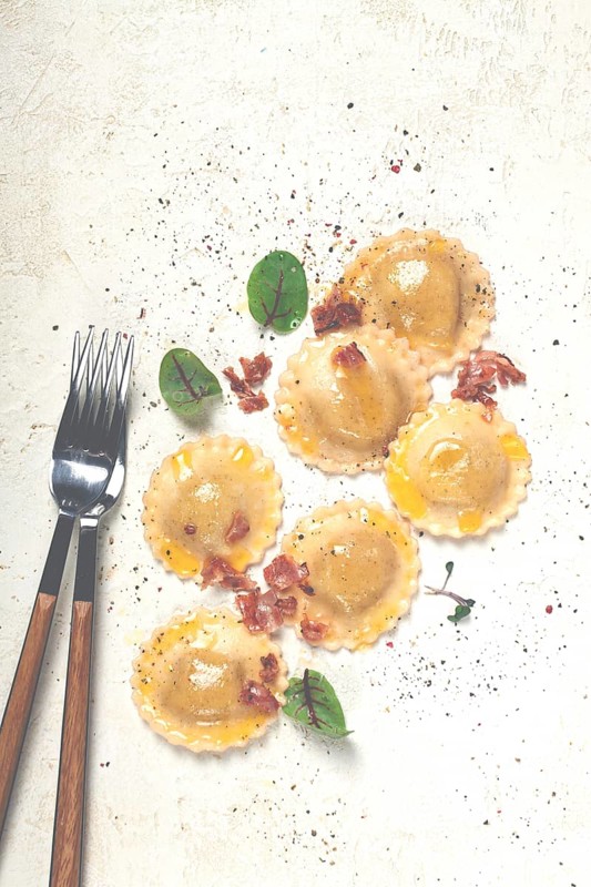 Fresh ravioli, with butter, spices and herbs, fried bacon, on the table, top view, light background, no people