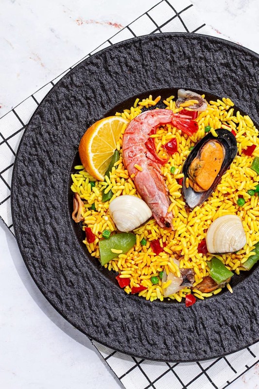Seafood paella on a black plate, no people