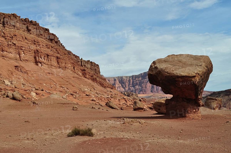 Huge single rock in a red desert landscape with cloudy sky, Grand Canyon National Park, Arizona, USA