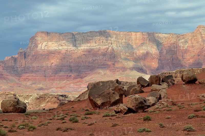 Large rocks spread across an impressive red desert landscape with dramatic skies, Grand Canyon National Park, Arizona, USA