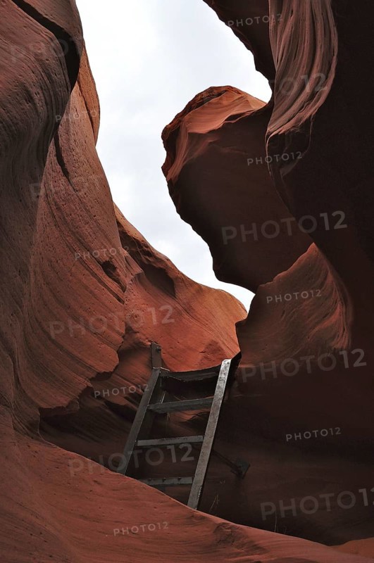 Steep sandstone rock walls with a ladder below and a view of the sky, entrance to Antelope Canyon, Navajo Nation Reservation, Lake Powell Tribal Park, Arizona, USA