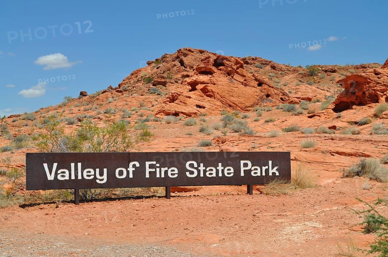Valley of Fire State Park sign against a red rocky landscape under a blue sky, Valley of Fire State Park, Nevada, USA