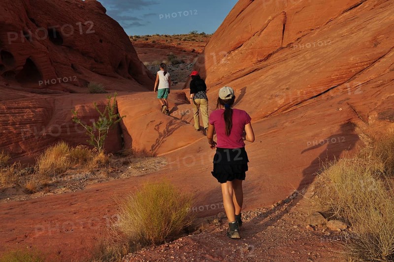 Group of hikers on a trail between red rocks in the desert, Valley of Fire State Park, Nevada, USA