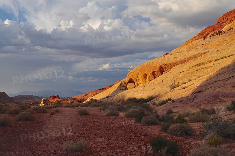 Wide landscape with cloud formations and illuminated red and yellow rocks, Valley of Fire State Park, Nevada, USA