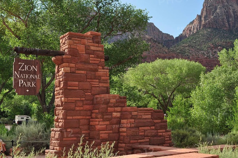 Brick monument with sign in Zion National Park, surrounded by green trees and mountains, Zion National Park, Utah, USA
