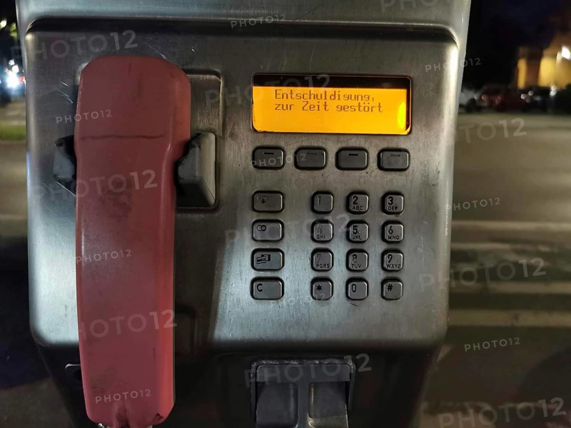 Public telephone at night, display shows error message, sorry currently disturbed, urban area, Berlin