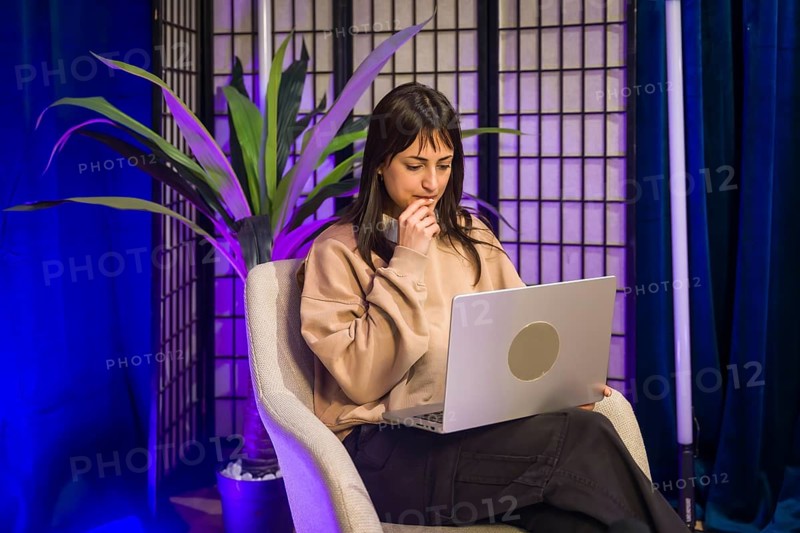Young woman focused at a laptop in a modern studio, planning and creating social media and podcast content for online audiences, remote work and digital entrepreneurship