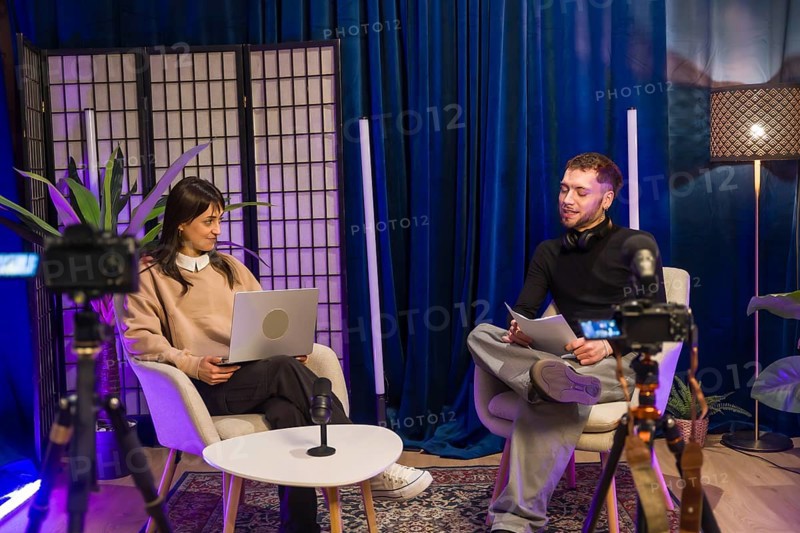 Content creators recording a video podcast or online interview in a broadcast studio, engaging with equipment for live streaming and social media production from home