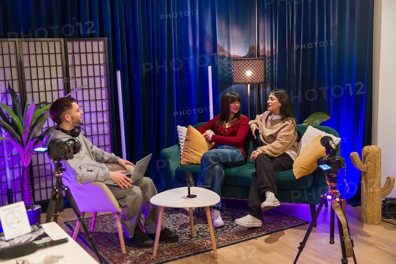 Young multiethnic creators collaborating on a podcast and social media video in a modern studio with cameras, microphones, lighting and casual, professional production setup