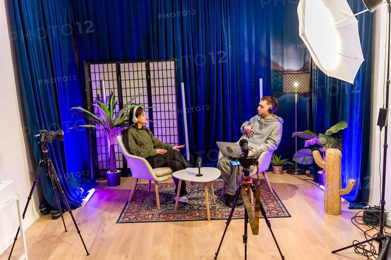 Young diverse people recording a social media podcast in a professional studio, creating digital content for online platforms with microphones, cameras, and lighting equipment