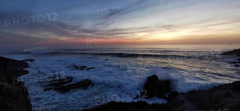 Dramatic sunset with dark clouds and waves, rocks in the foreground, hiking on the Fisherman's Trail, Southwest Alentejo nature park Park and Vicentina Coast, Portugal