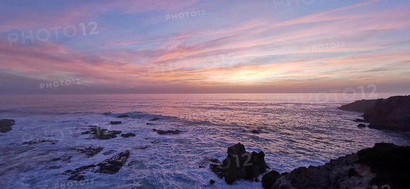 Romantic sunset over the sea with pink sky and dark rocks, hiking on the Fisherman's Trail, Southwest Alentejo nature park Park and Vicentina Coast, Portugal