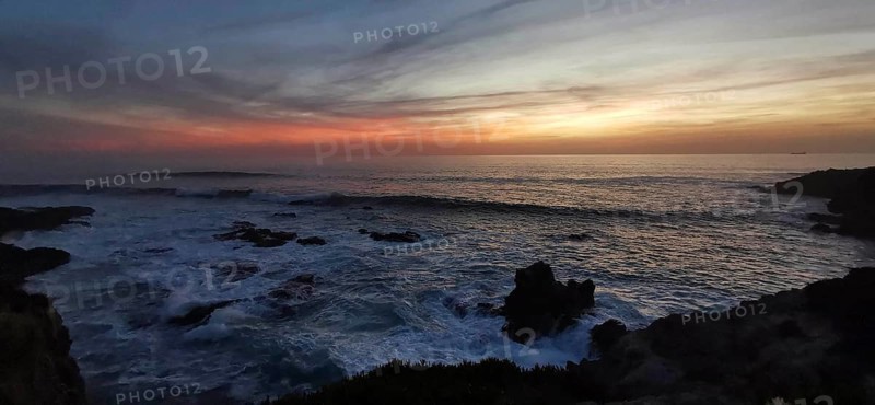 Subdued sunset with dark clouds and rocks in the sea, romantic atmosphere, hiking on the Fisherman's Trail, Southwest Alentejo nature park Park and Vicentina Coast, Portugal