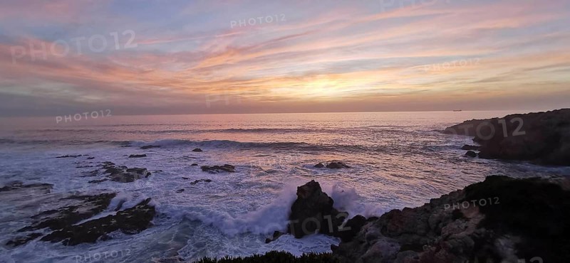 A gentle sunset with pastel-colored sky over the roaring sea, hiking the Fisherman's Trail, Southwest Alentejo nature park Park and Vicentina Coast, Portugal