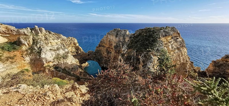 Archway, vast rocky landscape on the edge of the sparkling blue ocean, Lagos, Algarve, Portugal