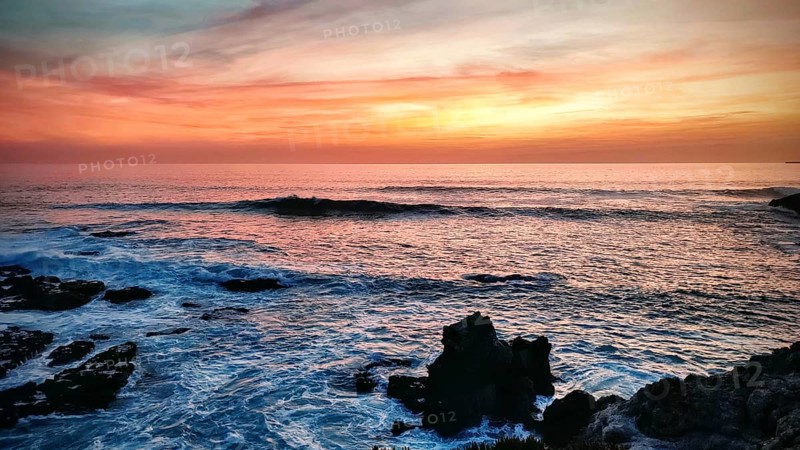 Impressive sunset with orange sky and dark rocks by the sea, hiking on the Fisherman's Trail, Southwest Alentejo nature park Park and Vicentina Coast, Portugal