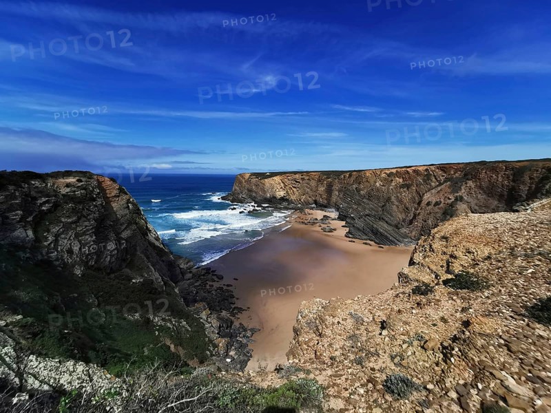 Extensive coastal view with dramatic cliffs and deep blue ocean under a clear sky, hiking on the Fisherman's Trail, Algarve, Portugal