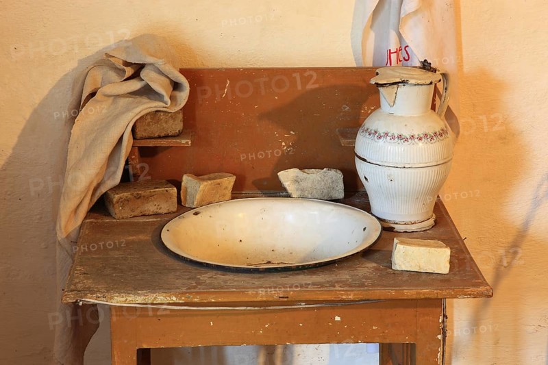 Antique washbasin with accessories, as used around 1900 in rural areas for daily body care. A large, white enameled or ceramic jug and a washing bowl, Lavoir, museum within the fortified church of Honigberg, Biserica Fortificata Harman, Transylvania, Romania
