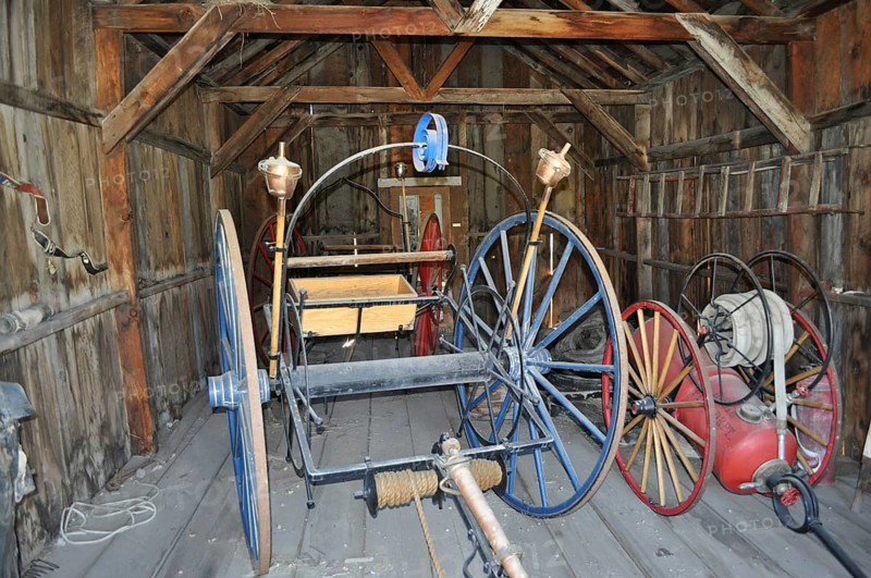 Antique tools and wagons in an old, abandoned wooden barn, fire engines, Bodie Ghost Town, California, USA