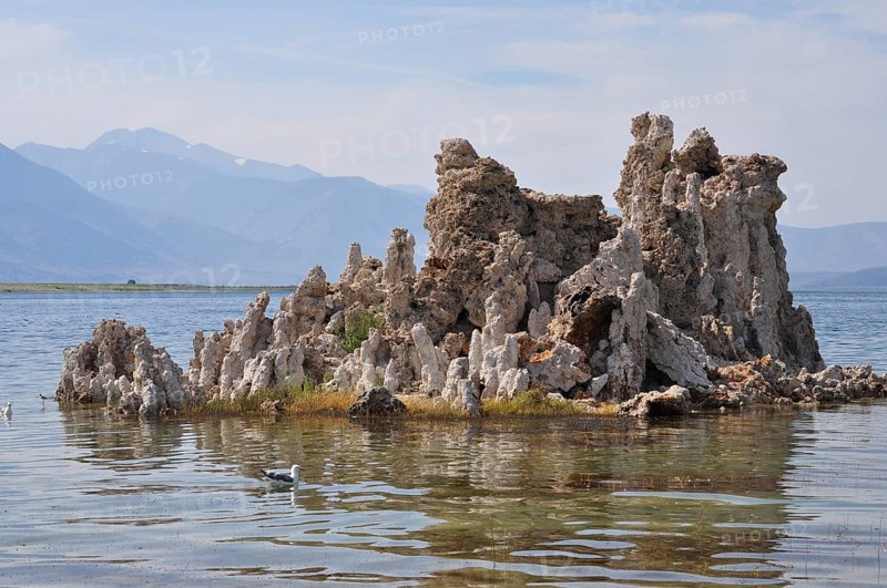Rocks, limestone formations, in a calm lake, Lake Natron, with mountains in the background, Mono Lake, California, USA