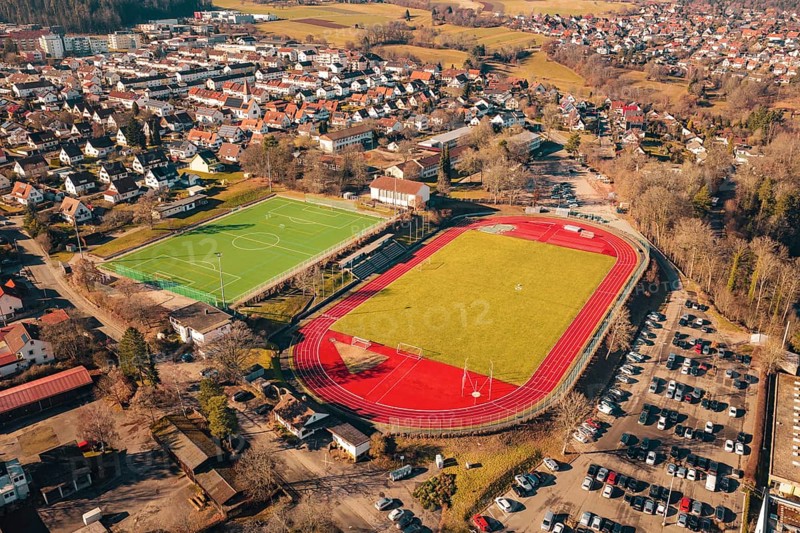 Stadium with soccer field and red track adjacent to a residential area, Wimberg, Calw, Germany
