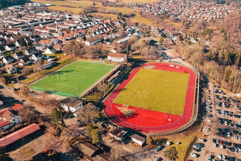 Two sports fields next to each other in a village, shot from the air, with running track and soccer field, Wimberg, Calw, Germany