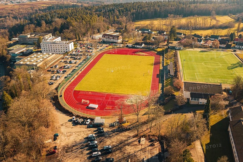 View of sports field with red track surrounded by trees and buildings, Wimberg, Calw, Germany