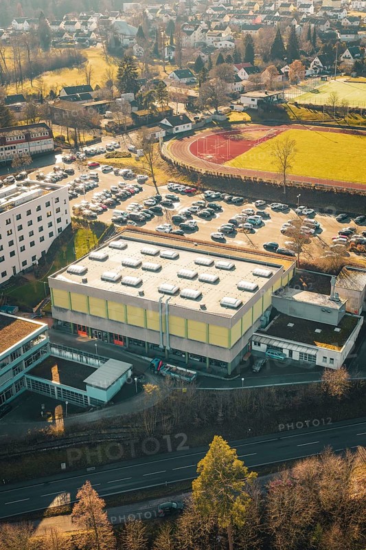 School complex with sports field and large parking lot, surrounded by winter countryside, Wimberg, Calw, Germany