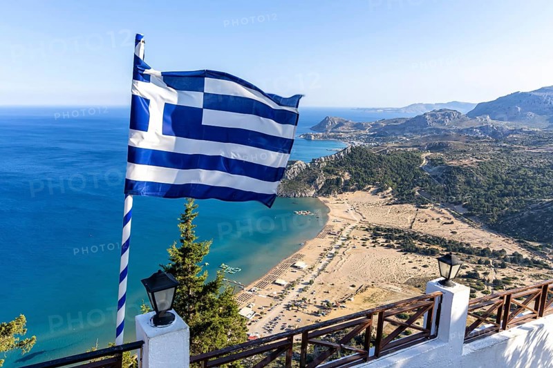 View of Tsambika beach from above with Greek flag Mediterranean seaside island of Rhodes, Greece