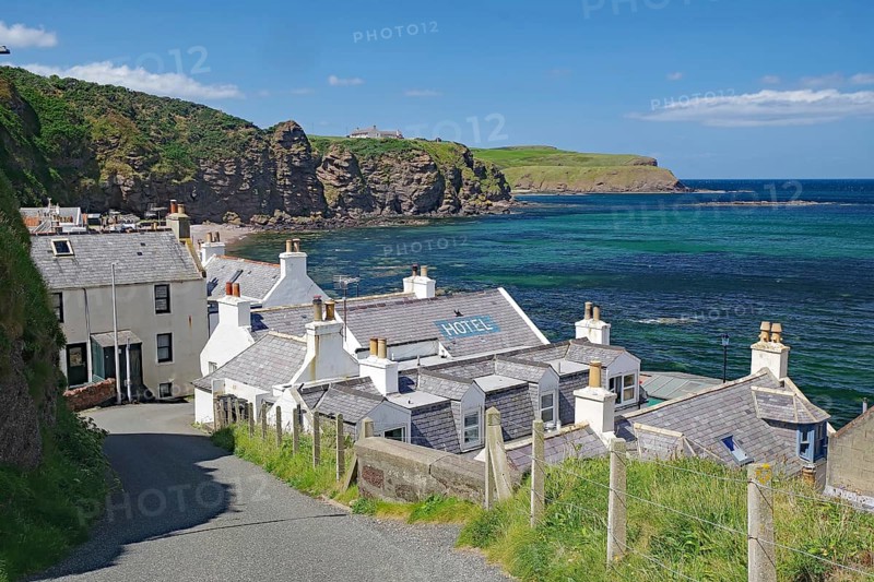 Village with hotel on coast with dramatic cliffs and blue water, Local Hero, Pennan, Aberdeenshire, Scotland, United Kingdom