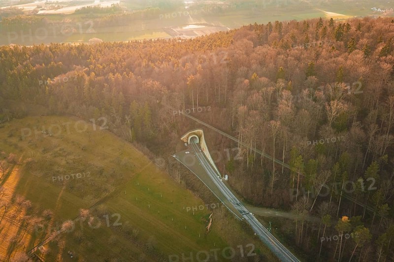 Aerial view of a wooded landscape with a winding road at sunset