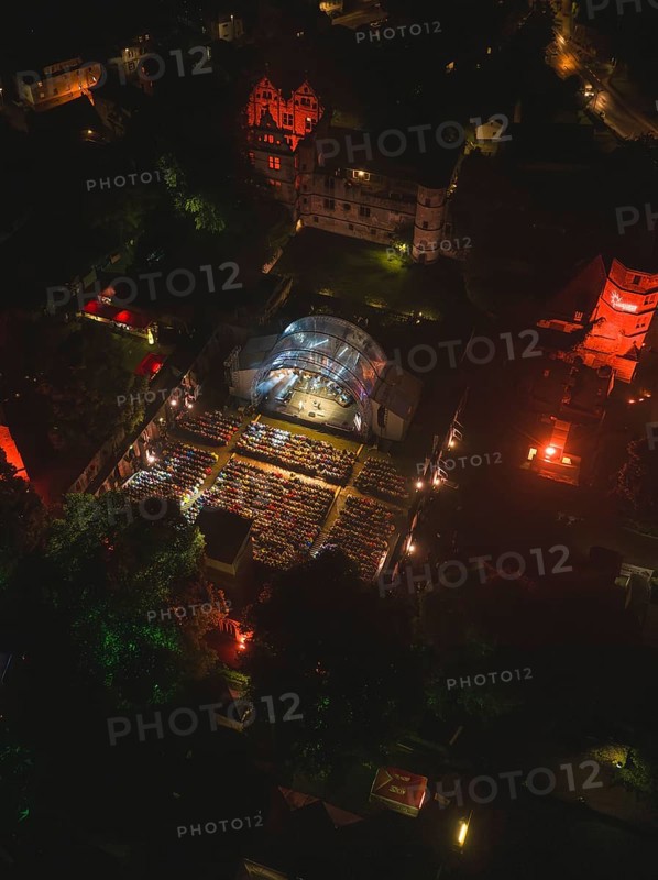Aerial view of an open-air concert at night with illuminated spectators
