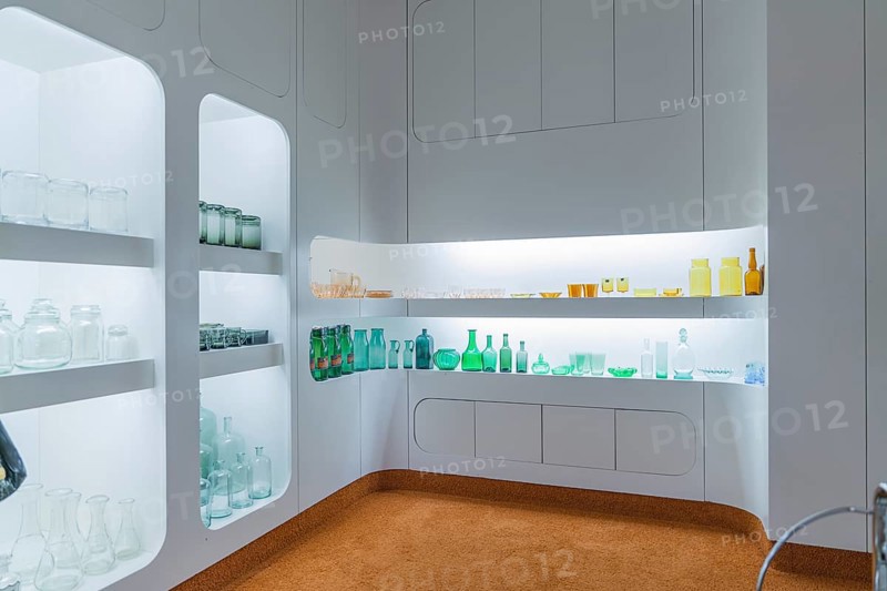 Interior with illuminated shelves full of glass bottles, modern white design