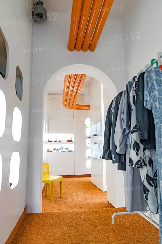 Modern interior with orange accents and a view of other rooms through an arch