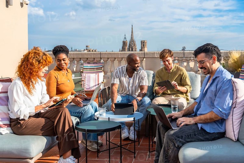 Diverse business colleagues working remotely from an outdoor rooftop office during a break, collaborating and communicating on a new startup project in the city