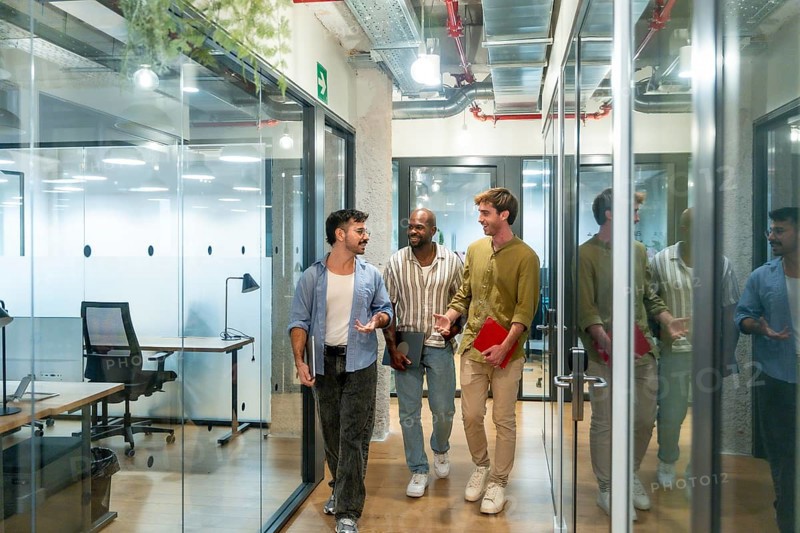 Diverse business colleagues walking and talking in a contemporary coworking office during a break, depicting teamwork, collaboration, and a strong professional relationship