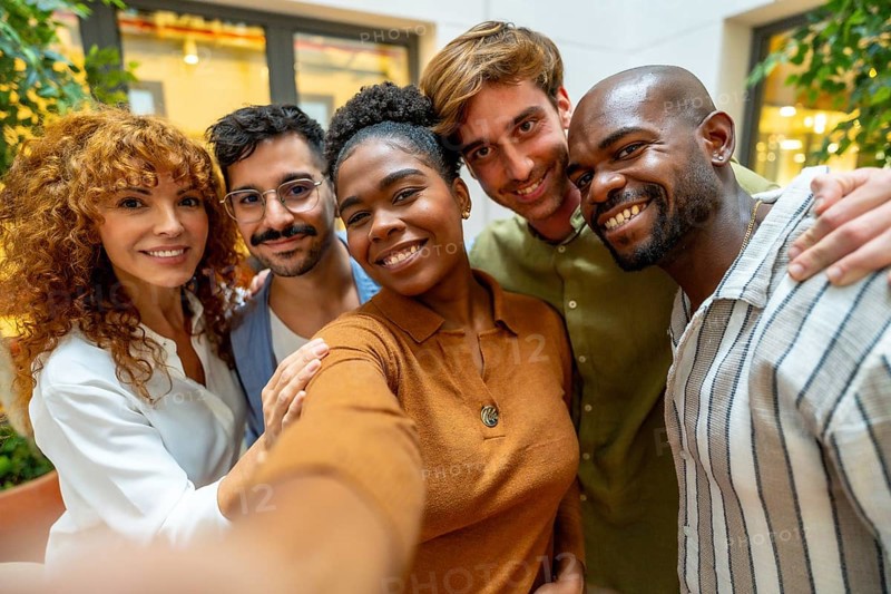 Diverse colleagues enjoying a moment together, smiling and embracing while posing for a self portrait, symbolizing teamwork, friendship, and positive workplace culture
