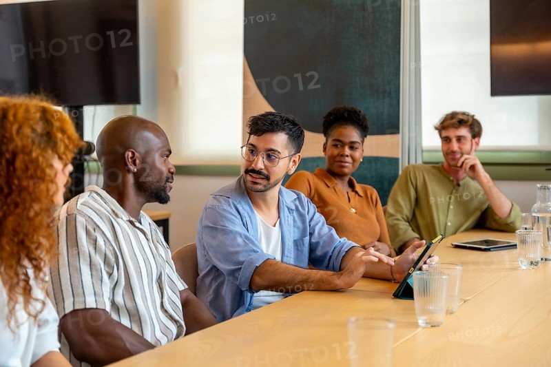 Diverse group of colleagues meeting in a modern office, collaborating and discussing ideas during a brainstorming session or break, fostering teamwork and professional interaction