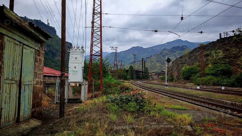 An abandoned railway line runs through a cloudy landscape surrounded by mountains, Armenia