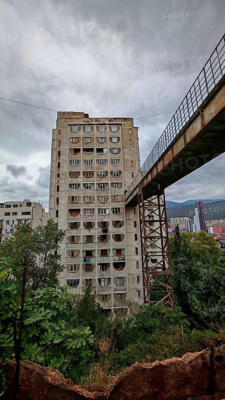 An old prefabricated building connected by a bridge with a grey sky, interesting building from a beautiful perspective, Tbilisi, Georgia