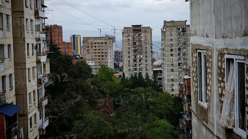 Old high-rise buildings with views of the city and surrounding trees, nostalgic curtain blowing from the window, Tbilisi, Georgia
