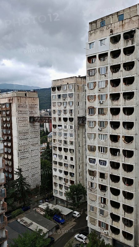 Three high-rise buildings connected by metal bridges under cloudy skies, nostalgic charm, architecturally interesting living silo, prefabricated buildings, Tbilisi, Georgia
