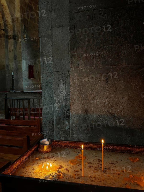 Candles burn in a dark stone church and create a peaceful atmosphere, Armenia