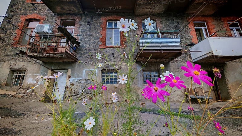 Colourful flowers in front of an old residential building with brick and wood, Armenia